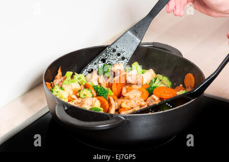 Rencontrez friture et légumes dans la poêle avec les mains Banque D'Images