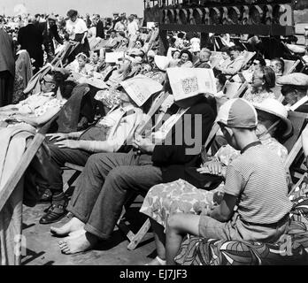 Deux gentleman assis sur une longue promenade de Blackpool, dans le Lancashire, portant des journaux sur leurs têtes comme des chapeaux improvisés. 26 juillet 1952. Banque D'Images