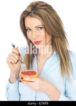 Attractive young woman eating a pamplemousse rose Banque D'Images