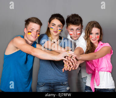 4 adolescents avec des drapeaux dessinés sur les visages des fans de soccer avec différents drapeaux peints sur les visages Banque D'Images