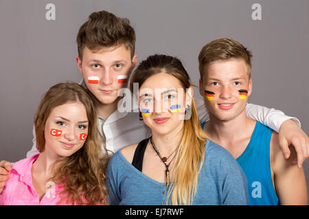 4 adolescents avec des drapeaux dessinés sur les visages des fans de soccer avec différents drapeaux peints sur les visages Banque D'Images