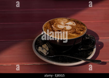 Cappuccino de chocolat saupoudré sur une table rouge. Banque D'Images