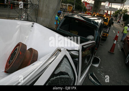 Manila, Philippines. Mar 23, 2015. L'un des roulements de la poutre de lancement qui s'est effondrée le long de l'Avenue d'Andrew toujours en haut d'une Suzuki Multicab tandis que la Toyota endommagée Revo est remorqué à déblayer la route. À environ 3 dans l'après-midi aujourd'hui, sur l'Avenue, près de Andrew Tramo à Pasay City, une poutre de lancement, à partir de la construction de l'autoroute de la NAIA, c'est effondré, causant des dommages à des voitures qui passent. Aucun rapport de blessés, mais l'incident endommagé au moins 5 voitures et provoqué un fort trafic le long de l'Avenue d'Andrew. Crédit : J Gerard Seguia/Pacific Press/Alamy Live News Banque D'Images