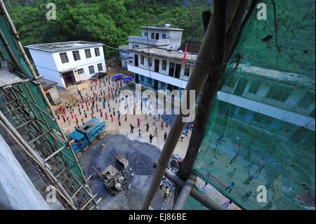 (150323) -- BANSHENG, 23 mars 2015 (Xinhua) -- Les élèves de faire les exercices sur leur nouveau terrain de jeu à l'école primaire en Nongyong Bansheng County, Chine du Sud, région autonome Zhuang du Guangxi, le 18 juin 2014. L'école primaire Nongyong a été construit en 1964. Il est situé à Bansheng County, une région rurale de la topographie karstique dans le Guangxi. Son premier bâtiment de l'école se compose de 12 maisons à un étage. Dans les années 1990, un bâtiment de deux étages et d'enseignement ont été construites avec. Il y a environ 250 élèves de tous les 22 villages de Nongyong. Chaque lundi, la plupart d'entre eux ont à marcher sur les collines sur le chemin de Banque D'Images