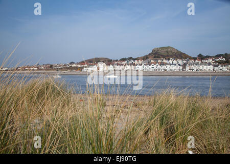 Vue depuis la plage / port en direction de Conwy Deganwy sur une journée de printemps ensoleillée avec vue sur la mer de l'herbe / dunes en premier plan Banque D'Images