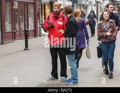 Tapin avec une grosse barbe de la Croix-Rouge britannique parlant à un donneur potentiel sur une rue de la ville Banque D'Images