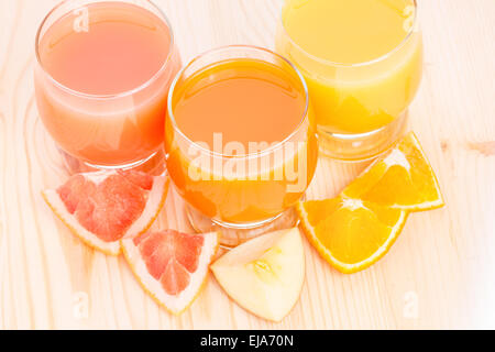 Vue de dessus du jus frais dans le verre avec des morceaux de divers fruits sur fond de bois. Vitamines santé Contexte Banque D'Images