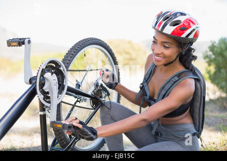 Fit woman fixant la chaîne sur son vélo Banque D'Images