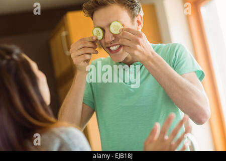 Cute man holding tranches de concombre sur les yeux Banque D'Images