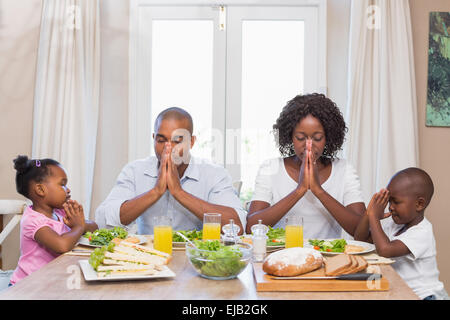 Famille heureuse disant grace avant repas Banque D'Images