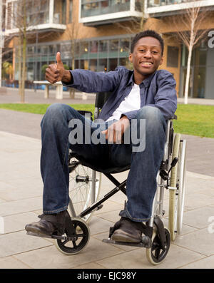 Jeune utilisateur de fauteuil roulant montrant le symbole de Thumbs up Banque D'Images