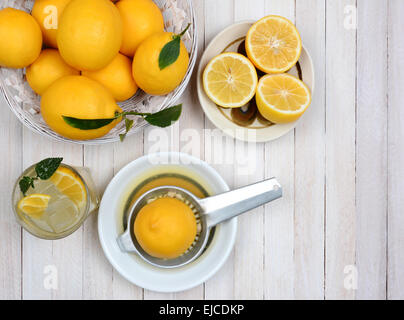 High angle shot de presser les citrons vie encore tourné d'un angle élevé sur une table de cuisine en bois blanc rustique. Banque D'Images