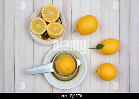 Presser les citrons still life tourné d'un angle élevé sur une table de cuisine en bois blanc rustique. Banque D'Images