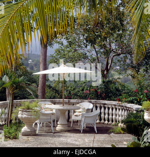 Parapluie blanc au-dessus des chaises en osier peint sur terrasse avec balustrade de pierre dans le jardin de Ste Lucie, West Indies Banque D'Images