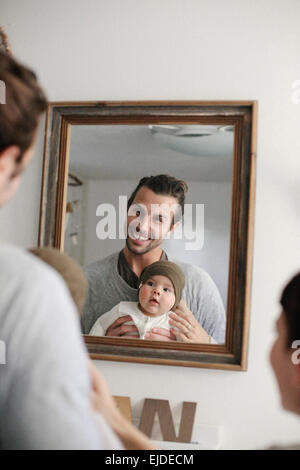 Un père et une mère avec son bébé, à la recherche dans le miroir. Banque D'Images