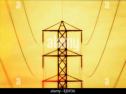 Un tour de l'hydro, un pylône d'électricité, structure métallique avec les lignes électriques de transport d'armes, contre un ciel jaune vif. Banque D'Images