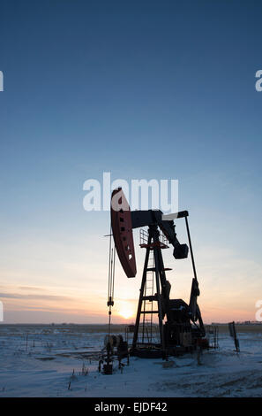 Une plate-forme de forage et de pumpjack sur une plaine dans les champs de pétrole au coucher du soleil. Banque D'Images