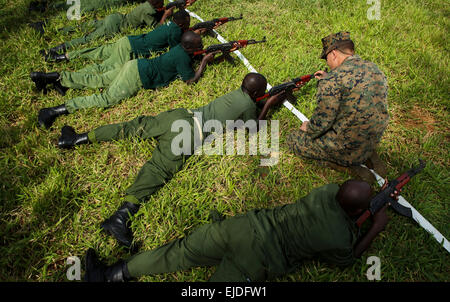 Un Marine américain avec l'outillage spécial air-sol marin crise Response-Africa Groupe de travail contribue à un park ranger tanzanien visent un fusil d'assaut AKM au cours d'un combat de classe d'adresse au tir au Selous 3 Mars, 2015 dans Matambwe, Tanzanie. Les marines sont des park rangers infantry tanzanien d'enseignement des compétences telles que les patrouilles, les tactiques offensives, la navigation terrestre et montées à l'aide à la lutte contre le trafic illicite. Banque D'Images