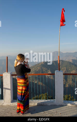 Une femelle de couleur vive dans un tourisme de prendre robe photos de Temple Kunjapuri près de Rishikesh, Inde, donnant sur l'Himalaya au coucher du soleil Banque D'Images
