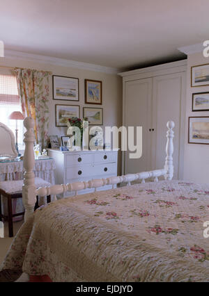 Courtepointe à motifs rose sur lit en bois laqué blanc en chambre cottage Banque D'Images