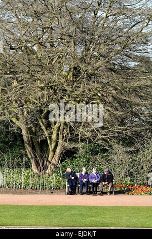 Groupe de personnes âgées assis sur un banc à Wisley Horticultural Gardens Banque D'Images
