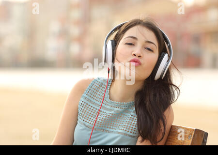 Funny teenager girl listening music with headphones kissing at camera Banque D'Images