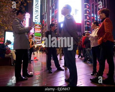 Les gens qui se trouvent en un point de rencontre sur la rue commerçante de Nanjing Road, Shanghai, Chine Banque D'Images