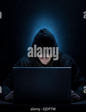 Homme cagoulé sur l'ordinateur, pour le piratage, espionnage, internet thèmes de sécurité Banque D'Images
