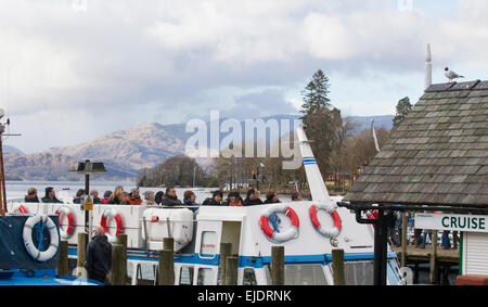 Le lac Windermere, Cumbria, Royaume-Uni. 24 mars, 2015. Météo : bateau de croisière arrive à l'embarcadère à l'atterrissage à Bowness-on-Windermere. Les touristes de profiter du soleil avec le dernier de la neige sur la haute lande Crédit : Gordon Shoosmith/Alamy Live News Banque D'Images