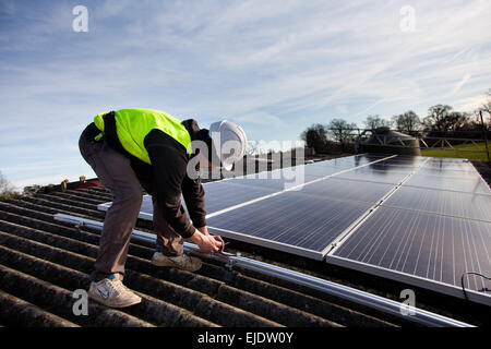 Jake Beautyman installe des panneaux solaires sur un toit de Grange Grange Farm, près de Balcombe. L'installation fait partie d'une initiative de Banque D'Images