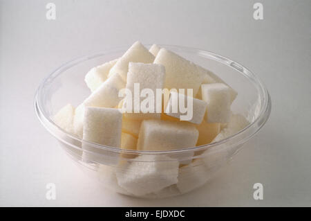 Bol en verre avec des morceaux de sucre sur fond blanc Banque D'Images