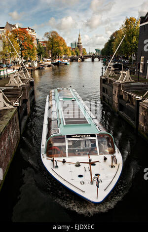 Bateau passant le Sint Antoniesluis vannes avec la tour Montelbaanstoren et canal Oudeschans à Amsterdam. Banque D'Images