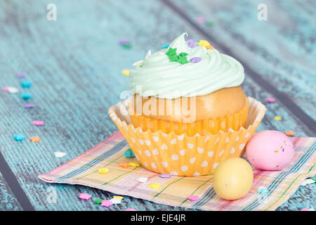 Cupcake de Pâques avec des bonbons et saupoudre sur fond vert vintage en bois Banque D'Images