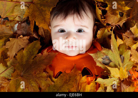 Sweet laughing baby fille jouant avec une énorme citrouille citrouille portant un chapeau tricoté sur fond blanc Banque D'Images