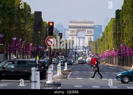 Un homme marche rapide à travers les Champs Elysées à Paris, France avec l'emblématique Arc de Triomphe au loin. Banque D'Images