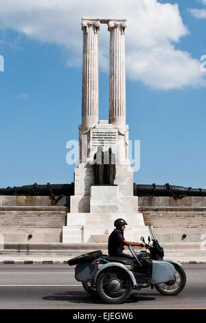 Un homme sur une moto vintage durs passé le monument aux victimes de l'USS Maine, construit en 1926, dans sur le Boulevard Malecon de La Havane, en l'honneur de 260 marins américains qui ont perdu la vie dans l'explosion de l'USS Maine le 15 février 1898 dans le port de La Havane. Le naufrage du Maine et de l'indignation des États-Unis sur l'Espagne la répression brutale de la rébellion cubaine ont conduit à l'éclatement de la guerre hispano-américaine en avril 1898. Banque D'Images