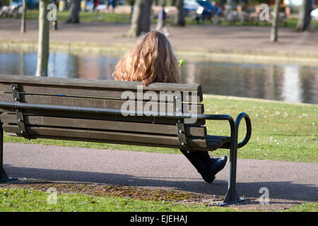 Les jeunes femmes checking mobile phone assis sur un banc sur le quai à Bedford, Bedfordshire, Angleterre Banque D'Images