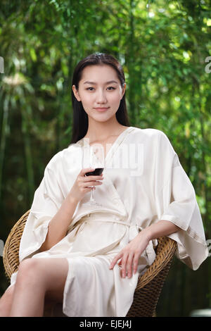 Une jeune femme portant un peignoir dans le verre de vin rouge Banque D'Images