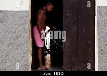 Un homme se tenant dans l'embrasure d'une roue de vélo dans les 500 ans de la ville de Sancti Spiritus, Cuba. Les Cubains passent beaucoup de temps à leurs portes et de nombreuses activités ont lieu sur la porte et la rue, créant un sentiment de communauté avec leurs voisins. Banque D'Images