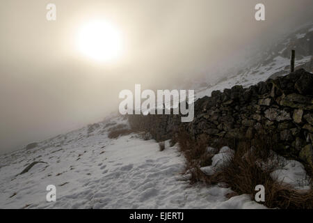 Bien passer à travers les nuages bas avec neige au sol en hiver. Ogwen Valley, Parc National de Snowdonia, le Nord du Pays de Galles, Royaume-Uni, Angleterre Banque D'Images