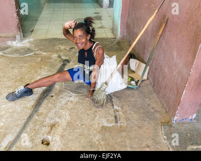 Une femme afro-cubaine femme de ménage pose et sourit alors qu'elle prend une pause de son travail de nettoyage sur le marché public. Banque D'Images