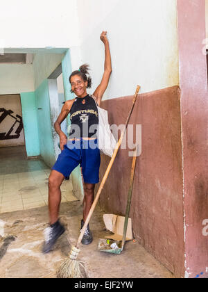 Une femme afro-cubaine femme de ménage pose et sourit alors qu'elle prend une pause de son travail de nettoyage sur le marché public. Banque D'Images