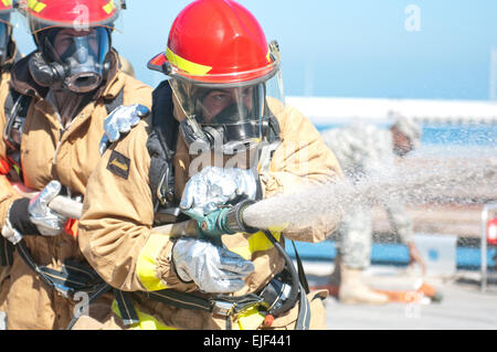 La CPS. Daniel Huntley, de Clayton, Californie, affecté à la 97e compagnie de transport bateau transport lourd, 10e Bataillon, 7e Brigade, expéditionnaire transport contrôle la direction de l'incendie alors que le PFC. Samantha Van Leer, de Berlin, N.J., bretelles sa coéquipière pendant une simulation d'incendie à bord du bateau de débarquement à Corinthe de l'utilitaire de la base navale de Koweït, le 24 janvier. Photos de l'Armée américaine par le sergent. Gene Arnold, Mobile 7e Détachement des affaires publiques Banque D'Images