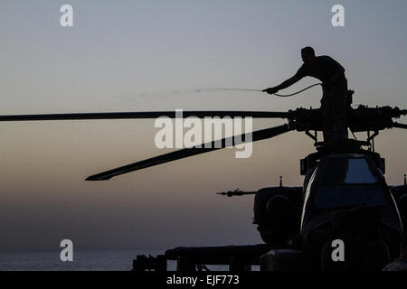 Des soldats américains avec l'attaque st 4-501Bataillon de Reconnaissance, 36e Brigade d'aviation de combat, nettoyer un AH-64D Apache après un exercice avec la Marine américaine alors que s'est lancé sur l'USS Ponce dans le golfe Arabo-Persique. La 36e CAB est actuellement déployée dans le Moyen-Orient, dans le cadre de l'opération Enduring Freedom. Banque D'Images