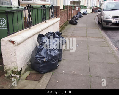 Sacs laissés sur le trottoir en face de maisons pour la collecte Banque D'Images