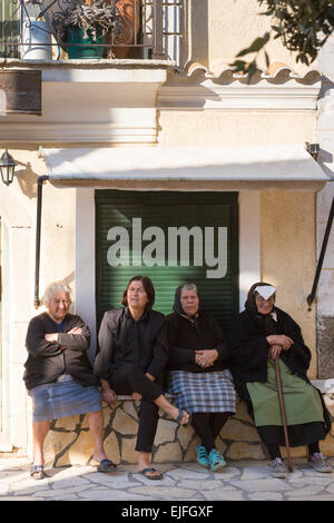 Corfou âgées femmes portant des vêtements noirs traditionnels de détente assis en place du village de Krini, Corfou, , Grèce Banque D'Images