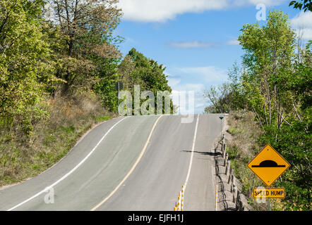 Hill on country road avec ralentisseur jaune panneau d'avertissement. Banque D'Images