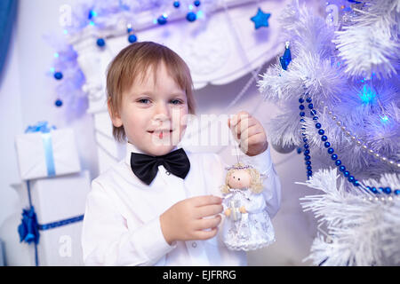 Petit garçon dans une chemise blanche et noeud papillon décore un arbre de Noël Banque D'Images