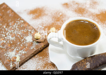 Tasse de café avec une mousse en forme de coeur subtilement décorées de fleurs et de chocolat en forme de banane Banque D'Images