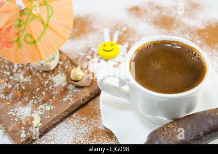 Tasse de café avec une mousse en forme de coeur subtilement décorées de fleurs et de chocolat en forme de banane Banque D'Images